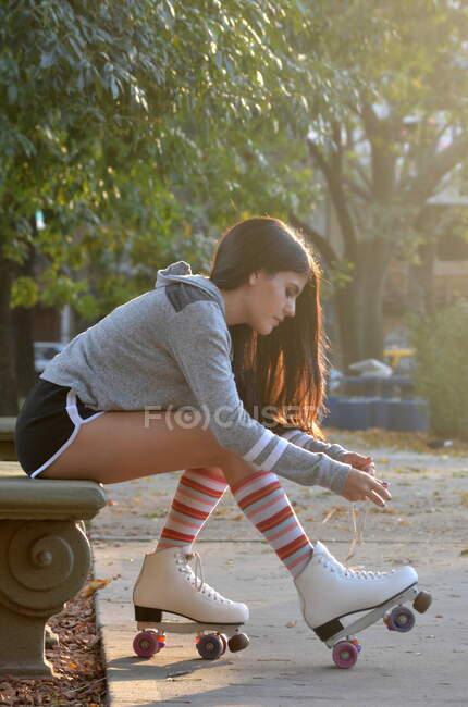 Chica atando los cordones de los zapatos en sus patines - foto de stock