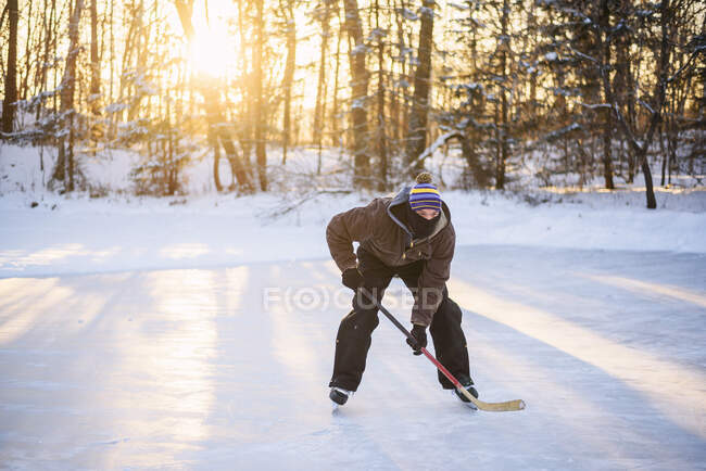 Uomo che gioca a hockey su ghiaccio su un lago ghiacciato — Foto stock