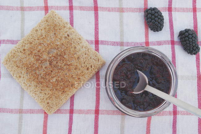 Кусок тоста с горшком ежевичного варенья — стоковое фото