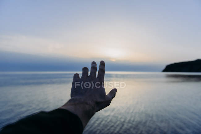 Man arm outstretched towards ocean water — Stock Photo