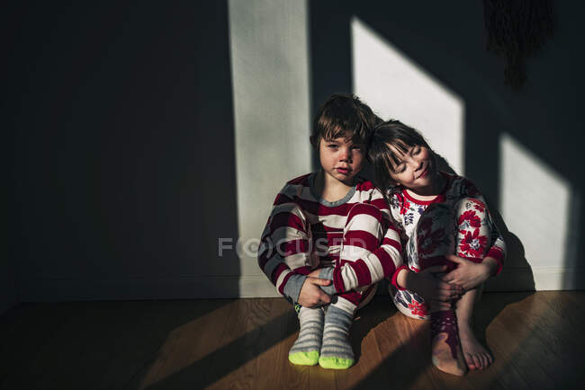 Garçon et fille assis sur le sol appuyé contre un mur — Photo de stock