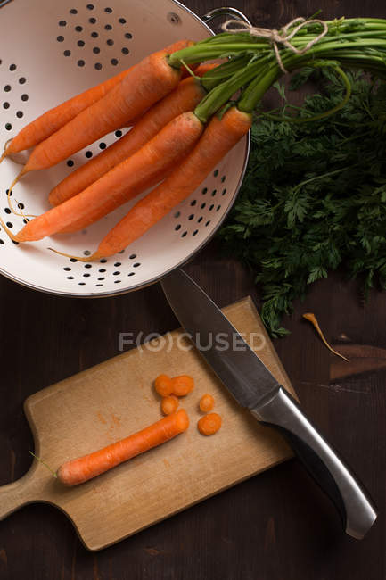 Cenouras em um escorredor e tábua de cortar — Fotografia de Stock