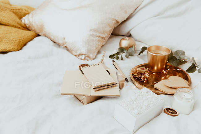 Wrapped gift, notepad and ornaments on a bed — Stock Photo