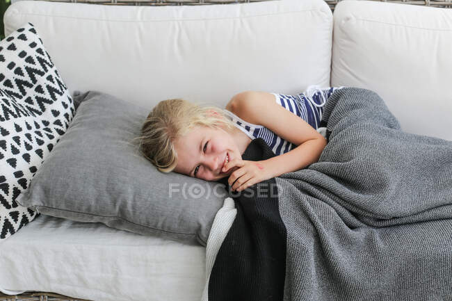 Девушка лежит на диване и смеется, — стоковое фото
