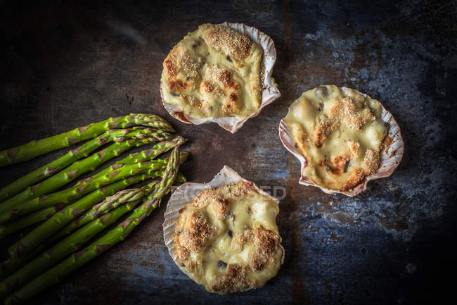 Mussel gratin in scallop shells with fresh asparagus, closeup view — Stock Photo