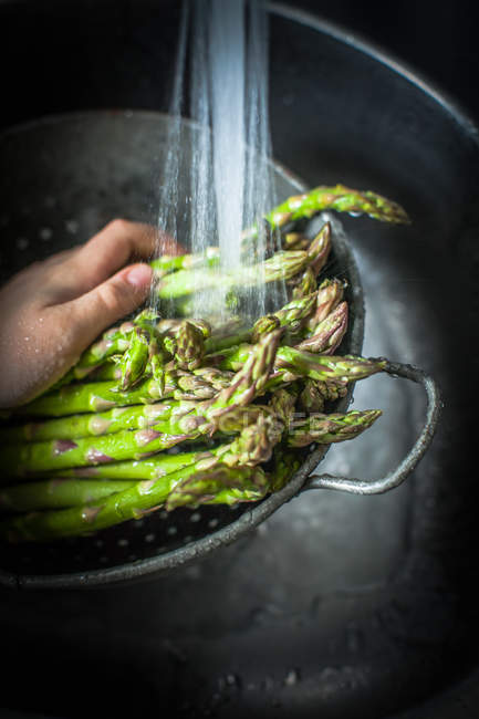 Man hand rinsing asparagus in water — Stock Photo
