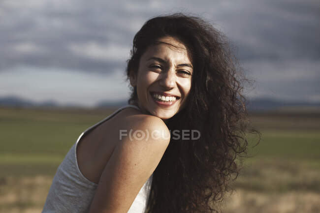 Portrait of a smiling woman sitting in a rural scene — Stock Photo