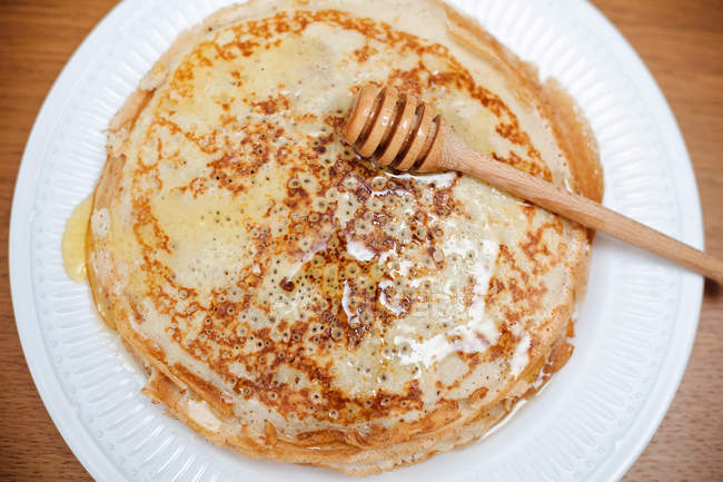 Plate of crepes with honey and a honey drizzler — Stock Photo