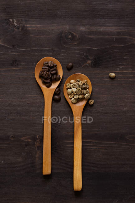 Dos cucharas de madera con granos de café - foto de stock
