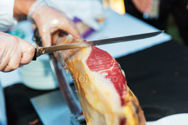 Man slicing a jamon with knife, closeup view — Stock Photo