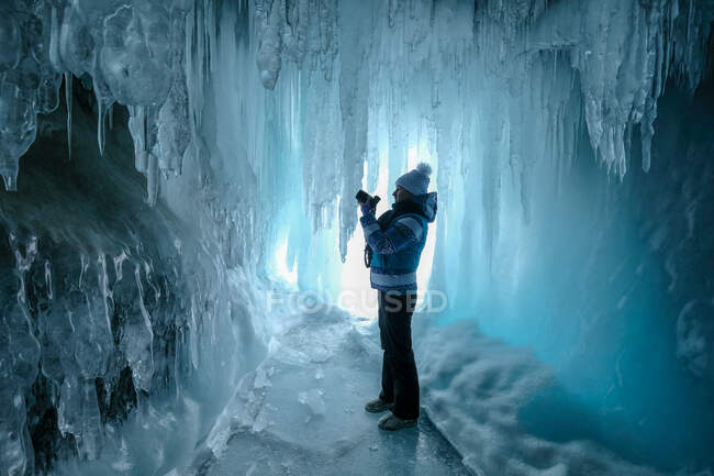 Mujer de pie en una cueva de hielo tomando una foto, Óblast de Irkutsk, Siberia, Rusia - foto de stock