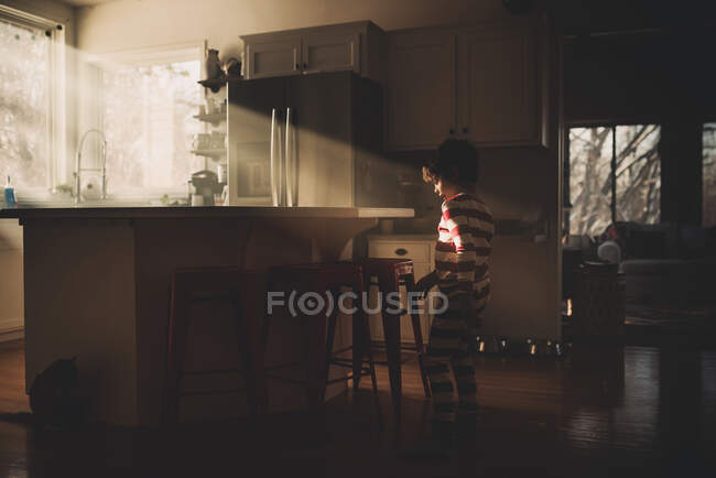 Garçon dansant dans la cuisine à la lumière du soleil — Photo de stock