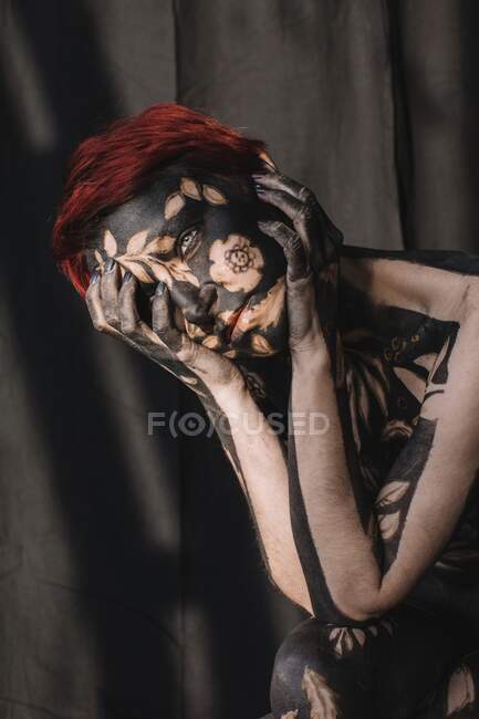 Portrait of a sad woman in black and gold body paint — Stock Photo