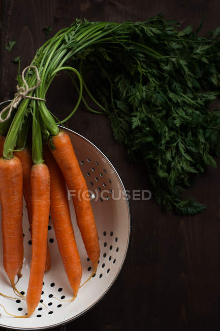 Fresh carrots in a colander, closeup view — Stock Photo