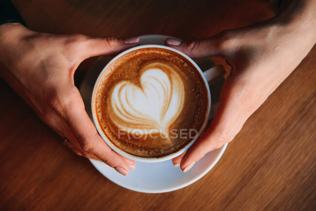 Main de femme tenant un cappuccino — Photo de stock