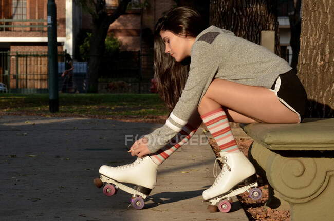 Chica adolescente atando cordones de zapatos en sus patines - foto de stock