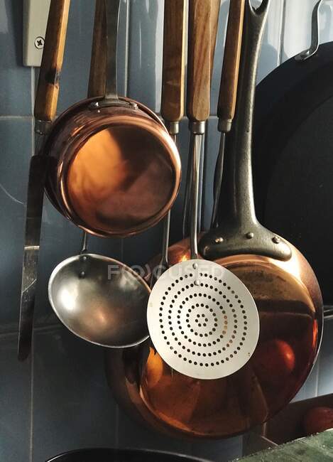 Panelas e utensílios de cozinha pendurados em uma parede — Fotografia de Stock