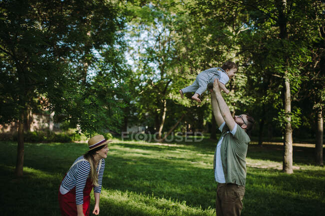 Madre y padre divirtiéndose con su hijo en el parque - foto de stock