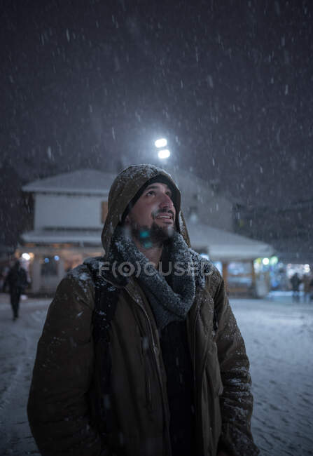Sorrindo homem de pé na neve na rua da cidade — Fotografia de Stock