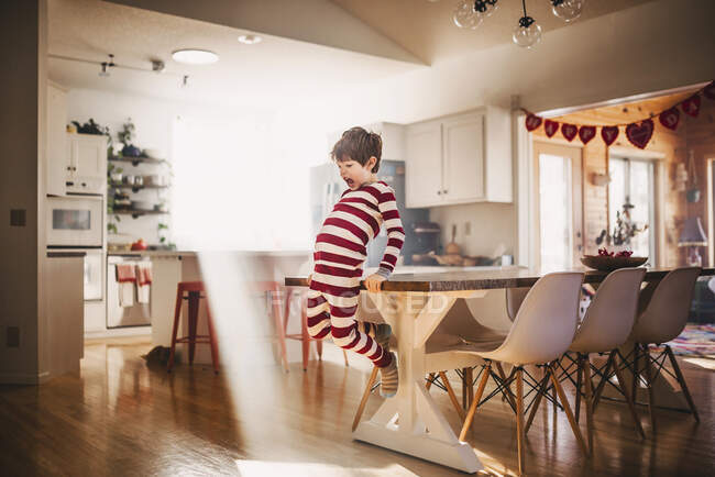Boy jumping off a dining room table — Stock Photo