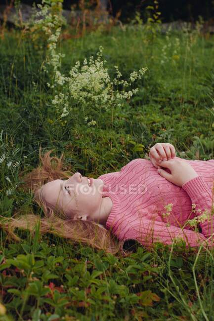 Lächelndes Mädchen mit ausgebreiteten Haaren im Gras liegend — Stockfoto