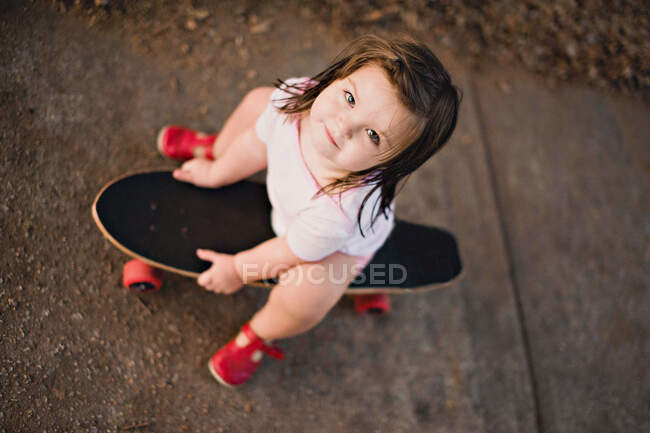 Ansicht eines Mädchens, das auf einem Skateboard sitzt — Stockfoto