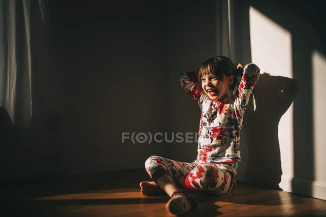 Menina sentada no chão em seu pijama rindo — Fotografia de Stock