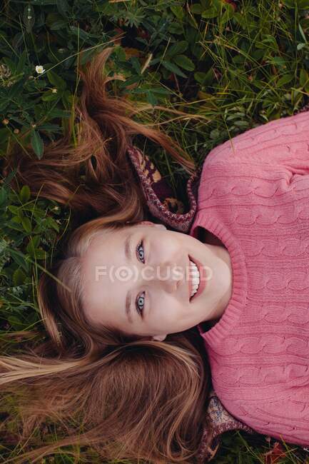 Lächelndes Mädchen mit ausgebreiteten Haaren im Gras liegend — Stockfoto