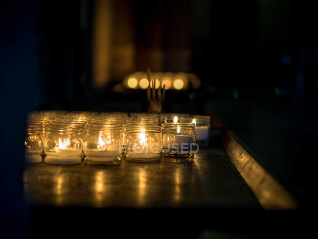 Té velas ligeras en una iglesia, Basílica de Sant 'Ambrogio, Milán, Lombardía, Italia. - foto de stock