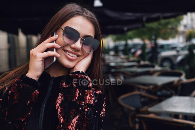 Donna sorridente che parla sul cellulare per strada — Foto stock