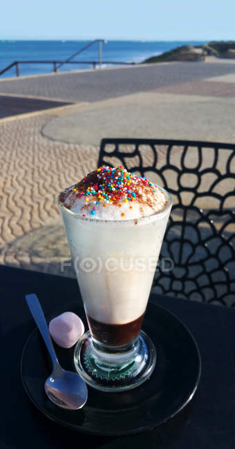 Babyccino with sprinkles and marshmallow on a table, closeup view — Stock Photo