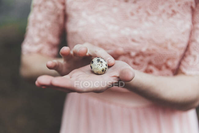 Main de femme tenant un oeuf de caille — Photo de stock