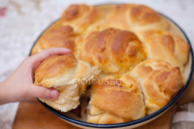 Junge Hand greift nach einem Stück bulgarischem selbstgebackenem Brot — Stockfoto