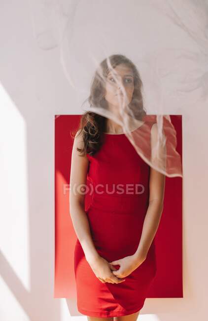 Портрет жінки, що стоїть біля червоної стіни за завісою — стокове фото