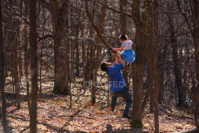 Girl climbing a tree with her father — Stock Photo