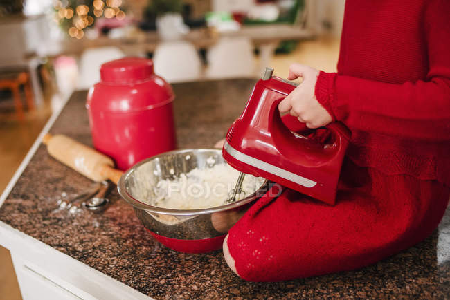 Girl sitting on a kitchen counter top making Christmas cookies — Stock Photo