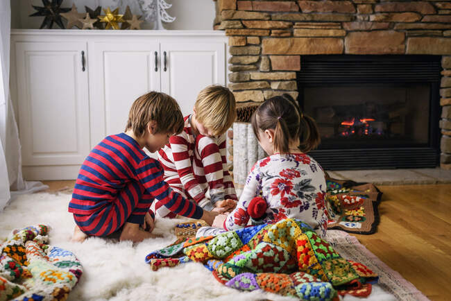 Three children sitting on the floor playing a board game — Stock Photo