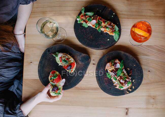 Woman eating appetizers with a glass of white wine and aperol spritz — Stock Photo