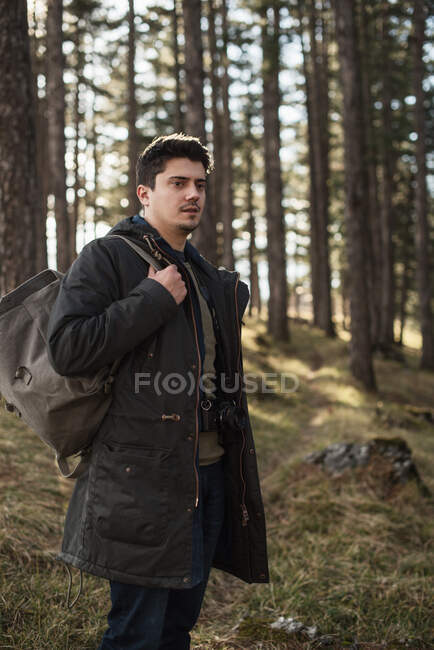 Uomo in piedi nella foresta con uno zaino — Foto stock