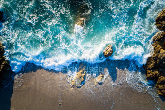 Воздушный вид на волны, разбивающиеся на пляже — стоковое фото