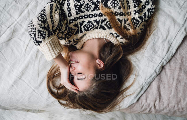 Lächelnde junge Frau liegt auf dem Bett — Stockfoto
