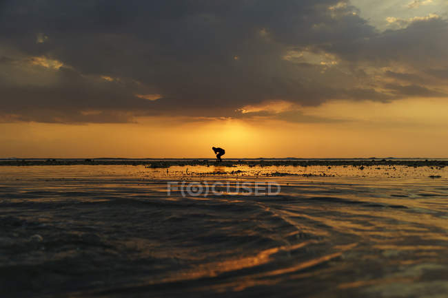 Силуэт человека, стоящего на пляже на закате, Индонезия — стоковое фото