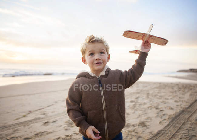 Boy standing on beach playing with a model aeroplane, Orange County, California, Estados Unidos - foto de stock