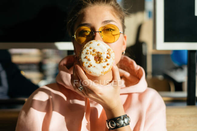 Portrait of a woman holding a doughnut in front of her face — Stock Photo
