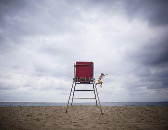 Boy jumping off a lifeguard chair on beach, Orange County, California, United States — Foto stock
