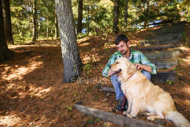 Чоловік і його собаки сидять на сходах в осінньому парку — стокове фото