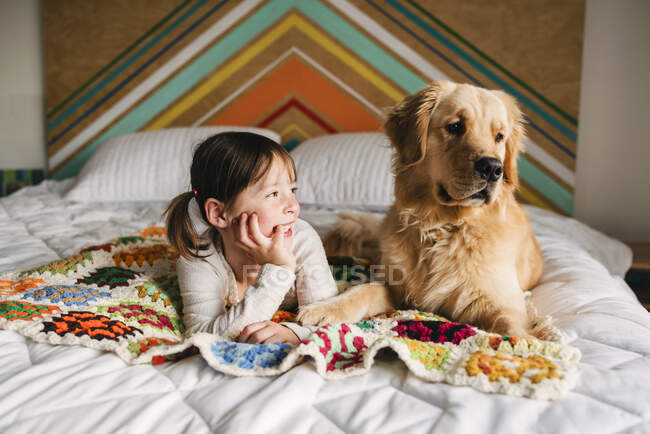 Jovem brincando com o cão em uma cama — Fotografia de Stock