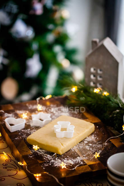 Christmas cookie dough on a wooden chopping board with decorations — Stock Photo