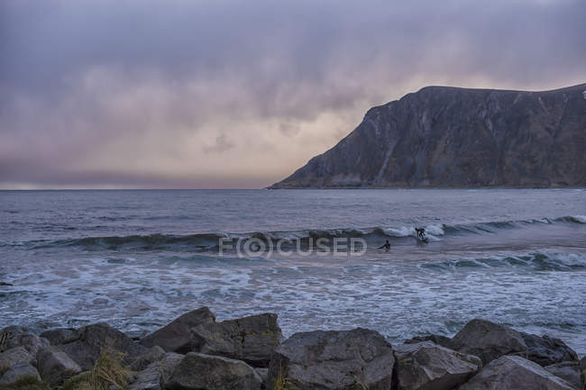 Vista panoramica di due surfisti nell'oceano, Flakstad, Lofoten, Nordland, Norvegia — Foto stock