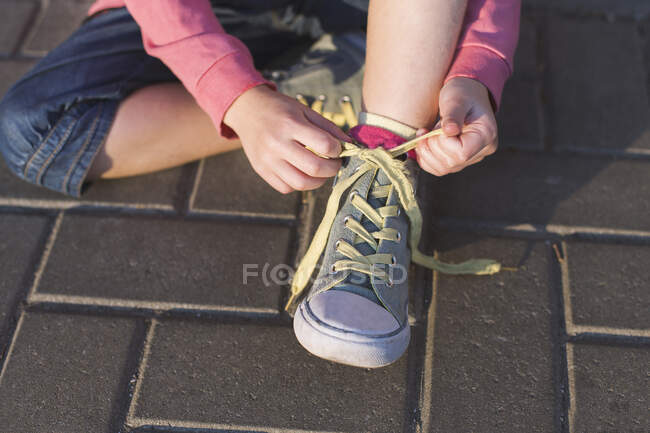 Mädchen sitzt auf dem Boden und bindet ihre Schnürsenkel — Stockfoto